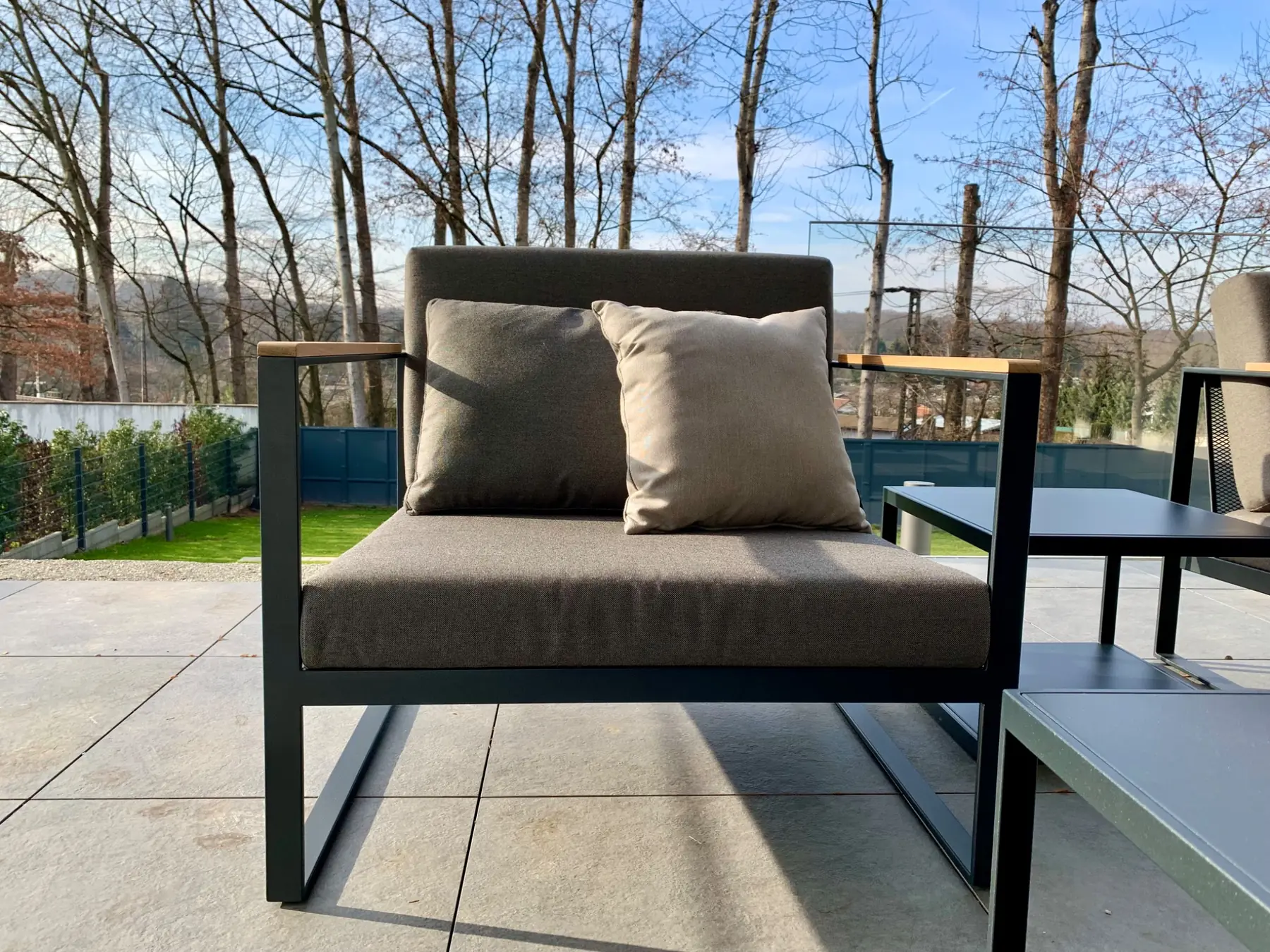 Outdoor-Lounge mit dunklem Metallrahmen und neutralen Polstern