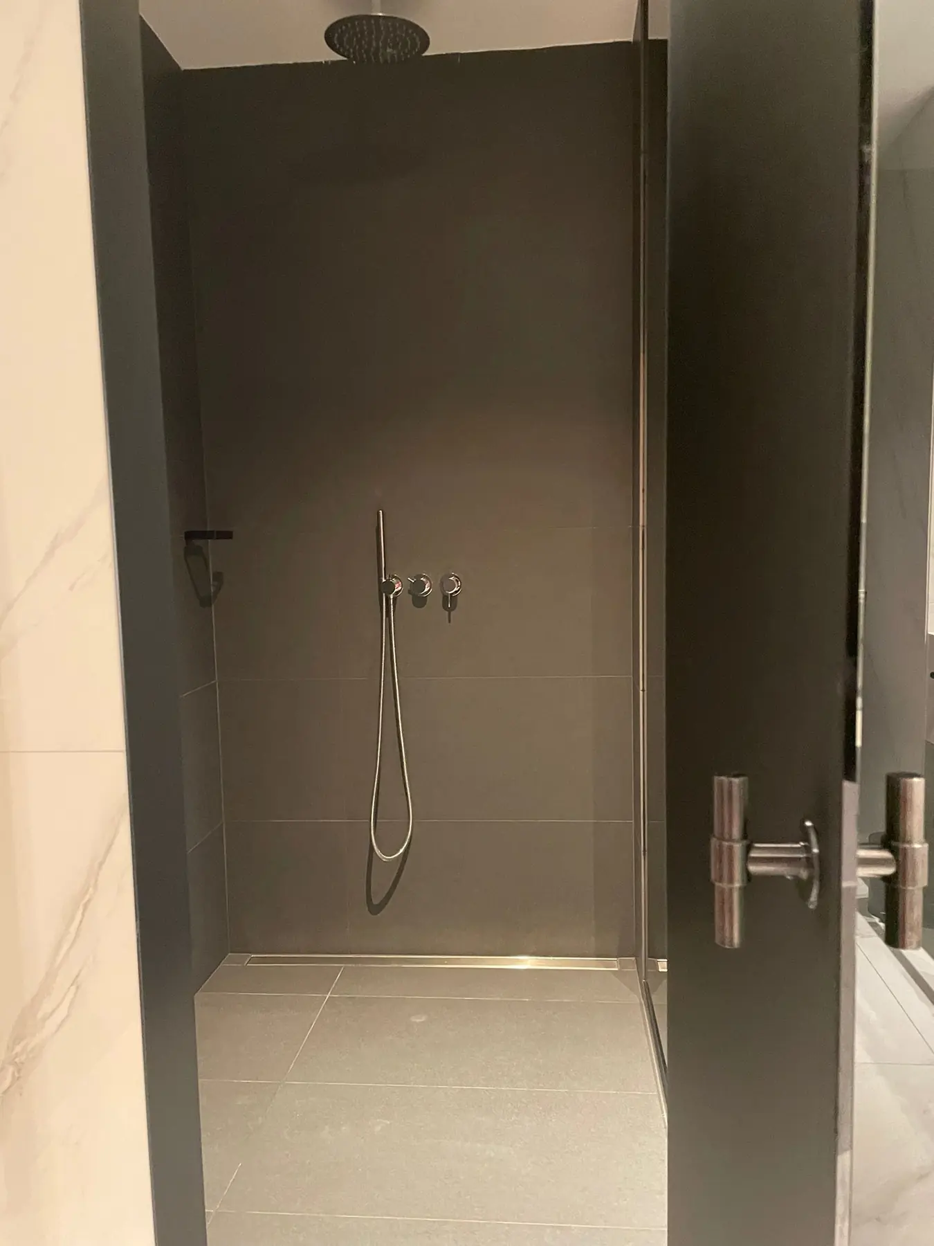 Bodengleiche Dusche in dunklem Grau mit schwarzer Regenbrause