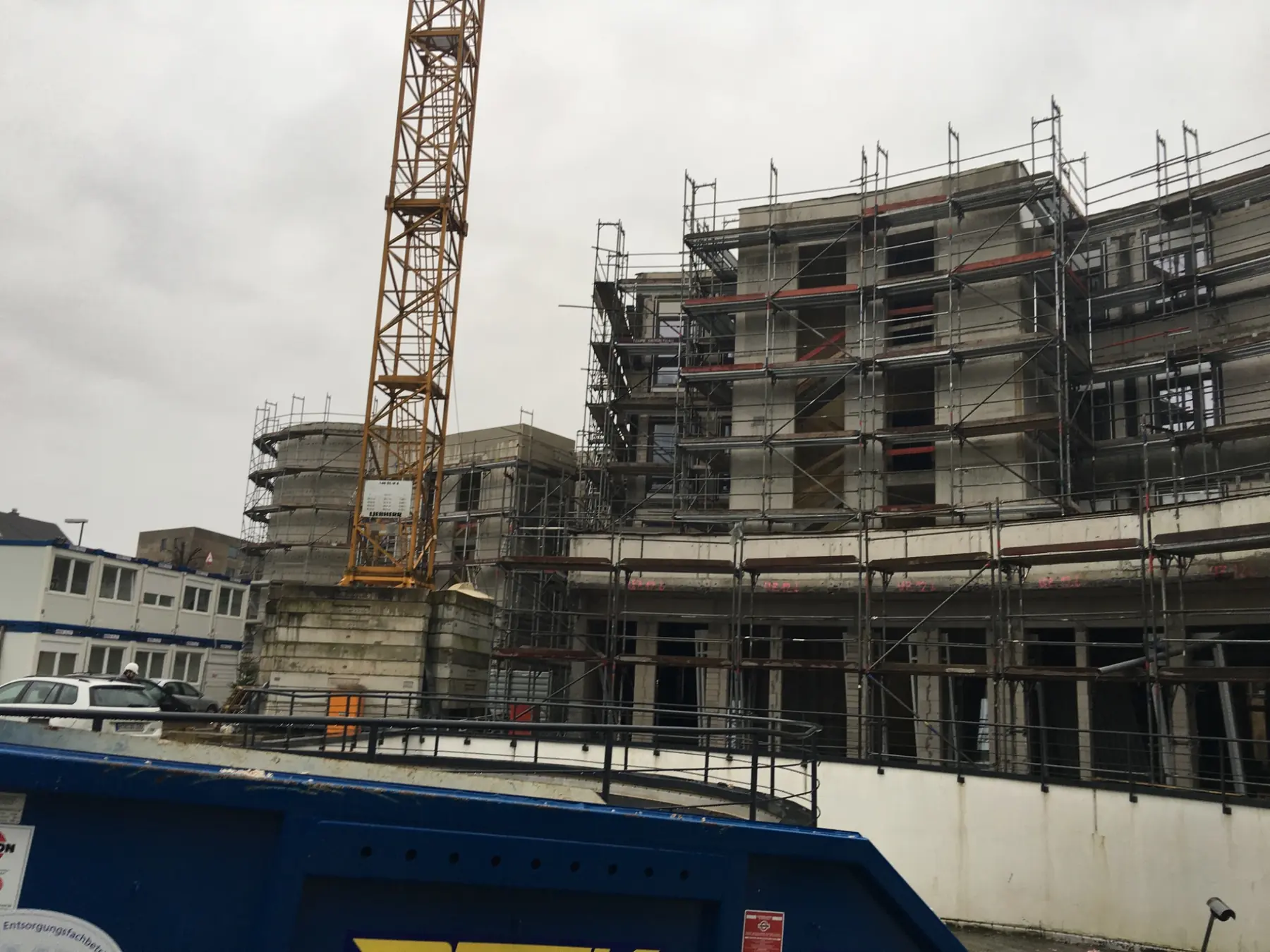 Rohbau eines mehrgeschossigen Wohngebäudes mit Gerüst und Baukran