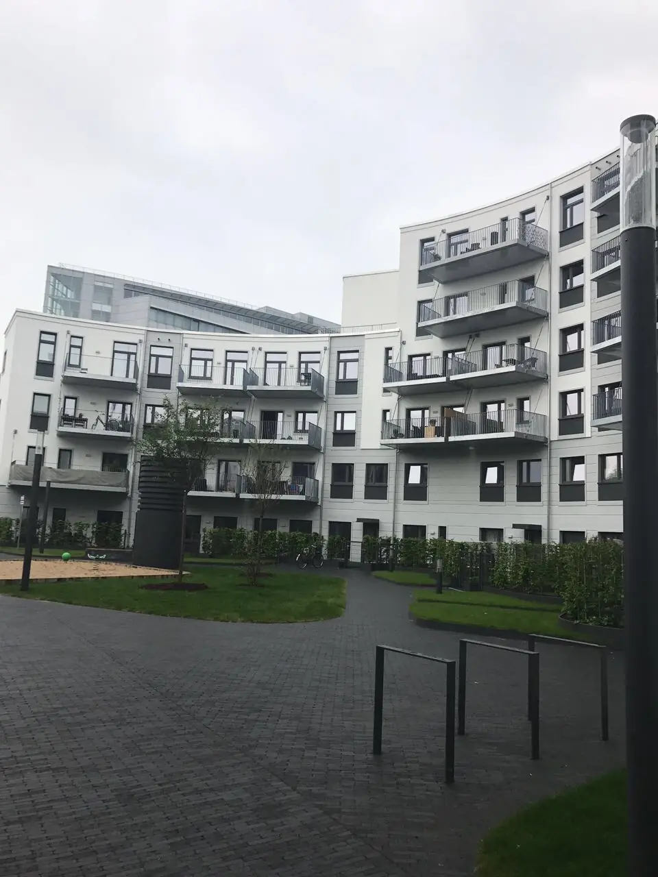 Moderner Wohnungsbau mit heller Fassade, Balkonen und Außenanlage