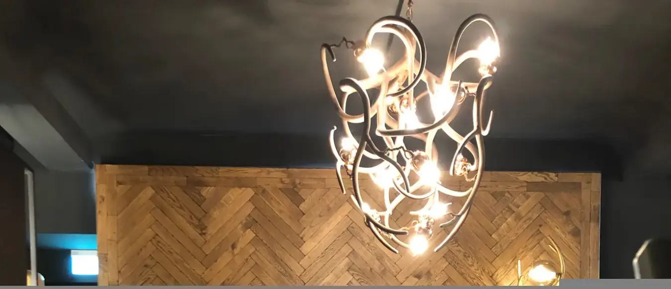 Detail einer Präsentationsfläche mit Fischgrät-Holzwand und Designbeleuchtung