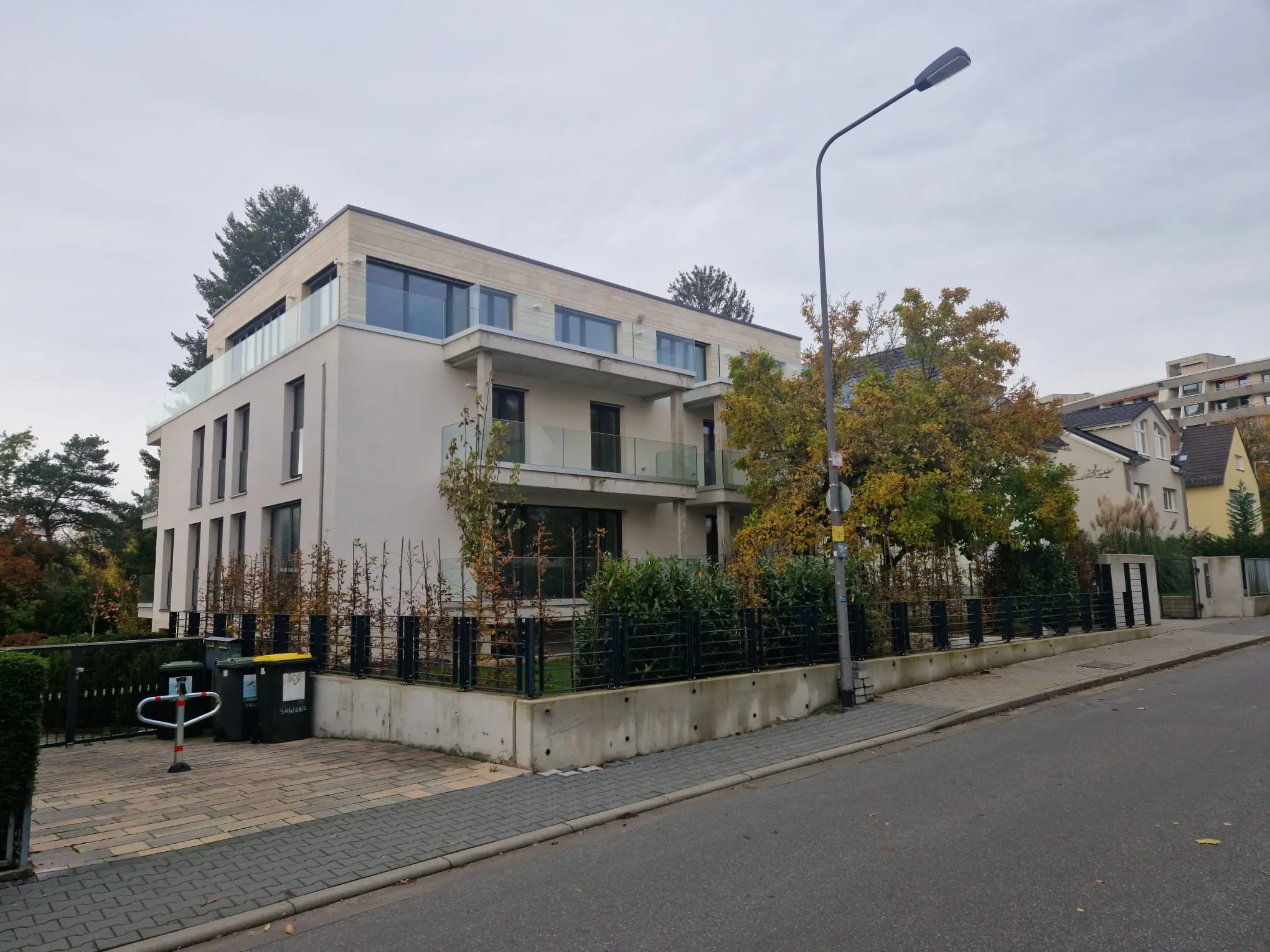 Fertiggestellter moderner Neubau mit Glasbalkonen und Außenanlage